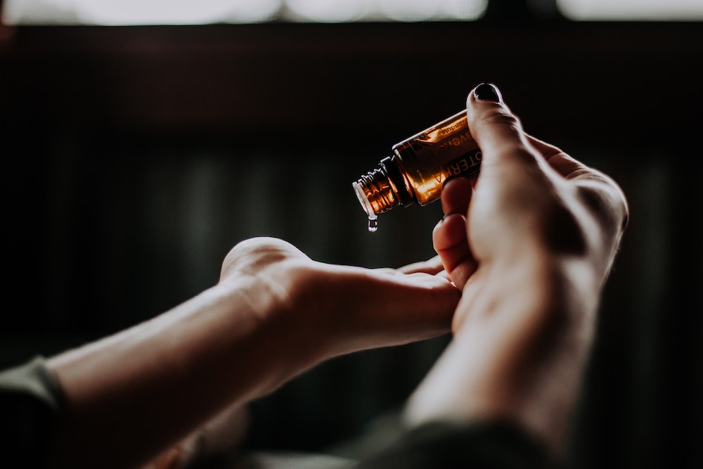 Hand pouring a drop of essential oils
